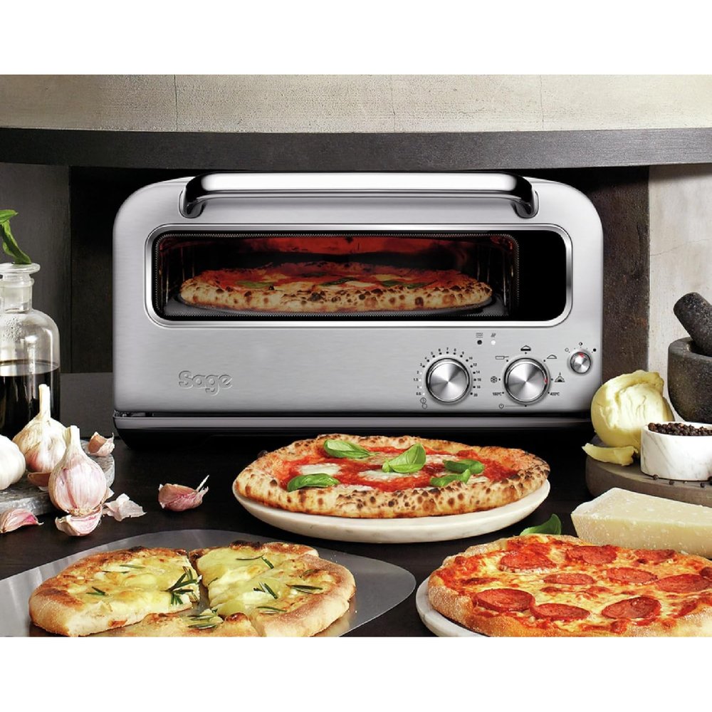 Le Smart Oven Pizzaiolo posé sur un plan de travail de cuisine, trois pizzas devant lui