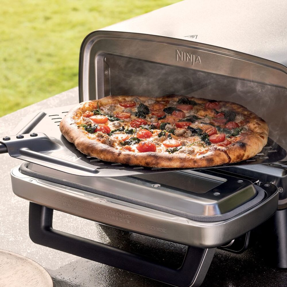 Pizza de 30 cm en cuisson dans le Ninja Artisan installé sur une terrasse